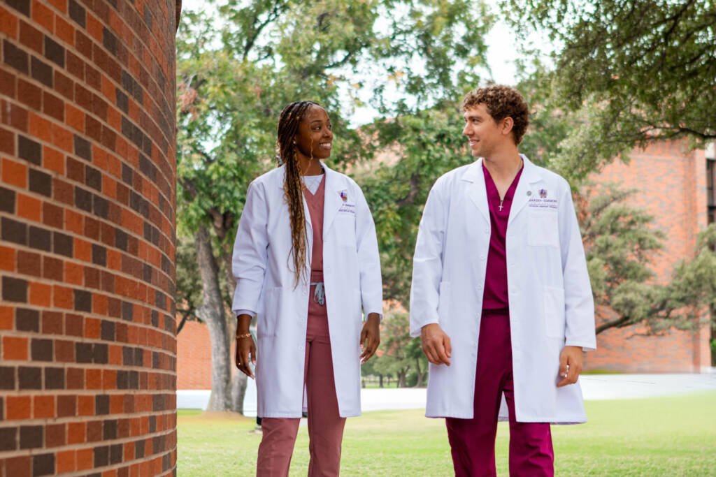 Two doctoral students walking by the alumni wall