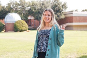 Sydney Smith smiles in front of Newman-Richardson Science Center at HSU.